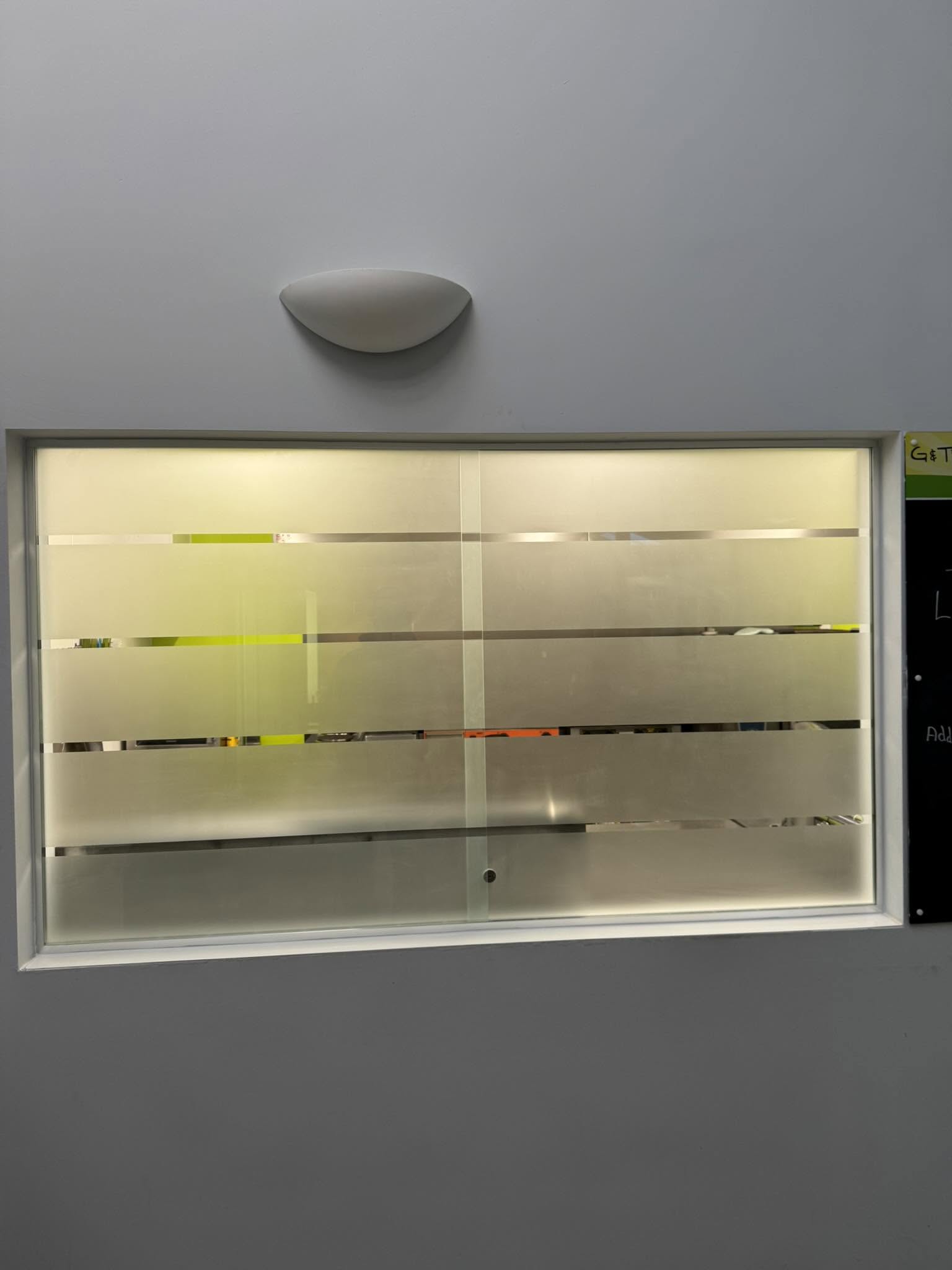 Frosted glass internal window with clear stripes, fitted in an office wall
